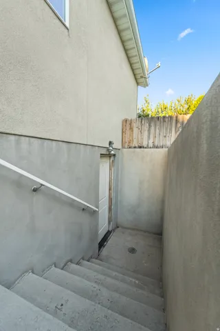Separate Entrance to Basement. Can be converted to Mother In Law Apartment. Concrete exterior stairs with a white handrail lead to a white entry door