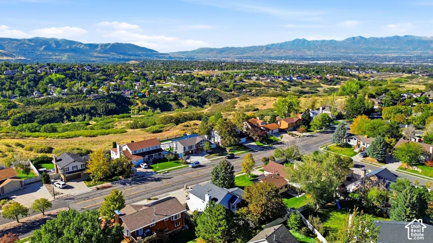 Residential neighborhood with established homes, mature trees, and mountainous topography