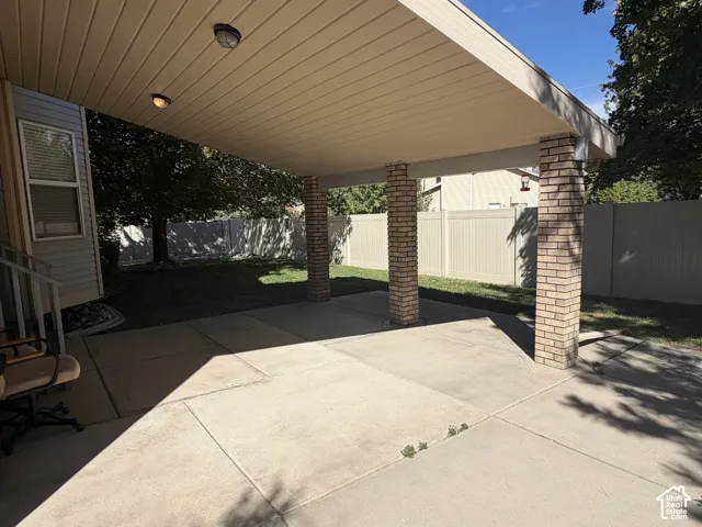 Covered patio featuring brick-clad support columns, integrated lighting, and concrete surfacing