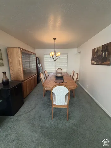 Wall-to-wall carpeting in a neutral tone, featuring a window with blinds, and an overhead chandelier with four light sources