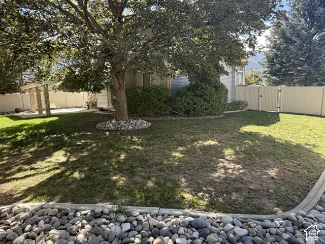 Lush green lawn with mature tree, surrounded by a stone border