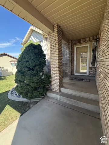 Brick exterior with covered entry, concrete steps, and a decorative security screen door