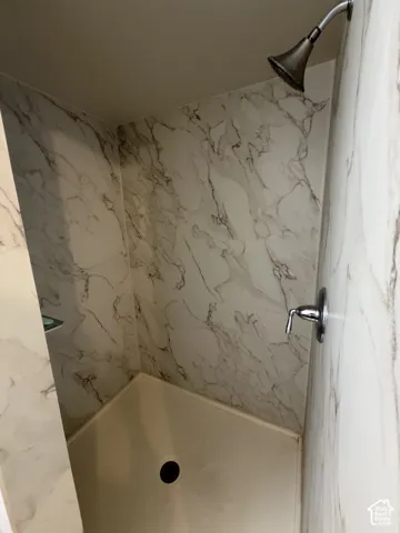 Shower stall with white and brown patterned walls and a bronze-finish showerhead