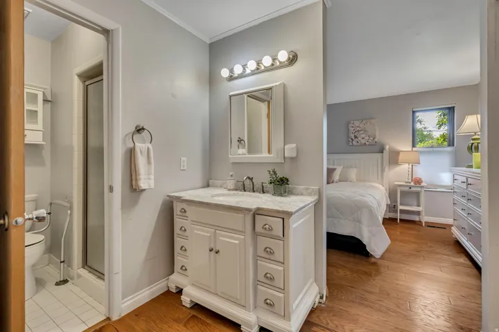 White vanity with a light-toned countertop, undermount sink, and decorative hardware