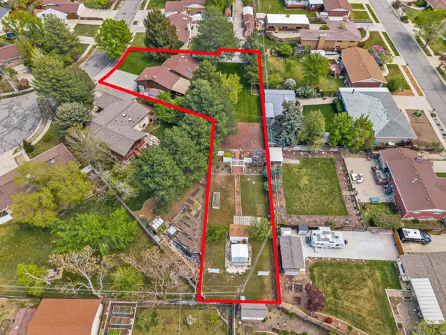 Aerial perspective showcasing a sprawling lot with established landscaping, multiple outbuildings, and a paved driveway