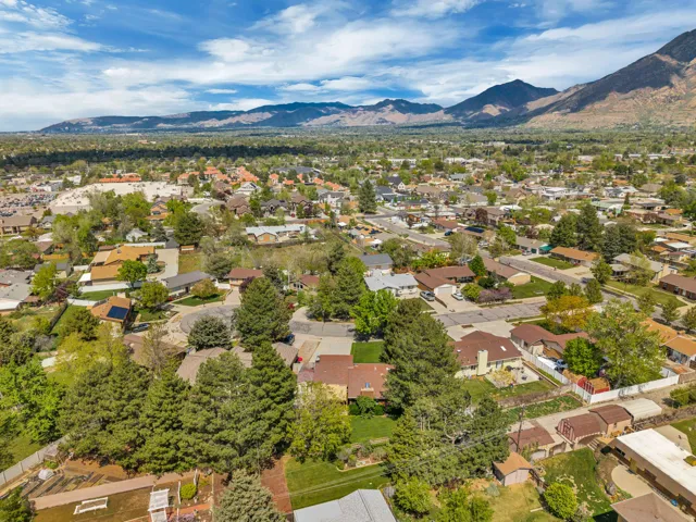 Expansive neighborhood setting with established residential properties, mature trees, and mountainous terrain in the background