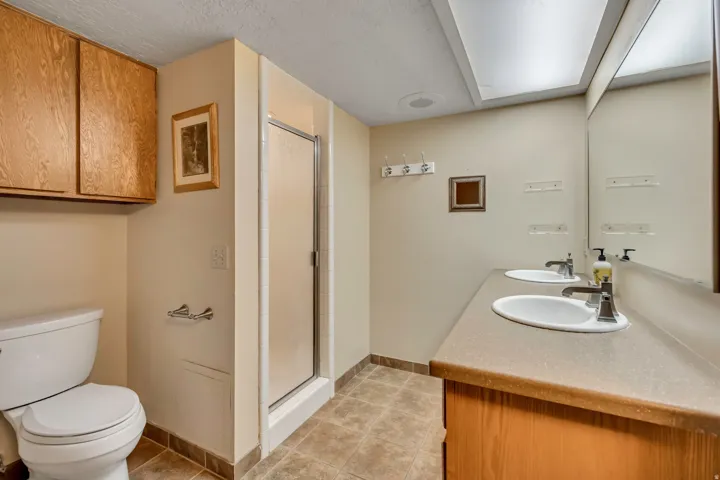 Dual vanity with undermount sinks, wood-finish cabinetry, and a full-width mirror