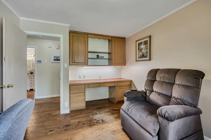 Built-in desk with overhead cabinetry, under-cabinet lighting, and wood-finish flooring