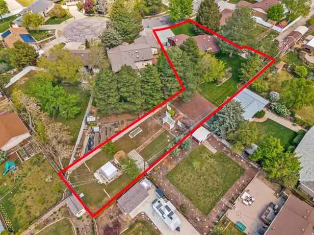 Expansive lot featuring mature trees, a manicured lawn, and multiple outbuildings