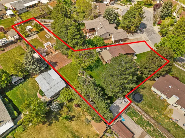 Residential property featuring a spacious lot, mature trees, and an extended driveway