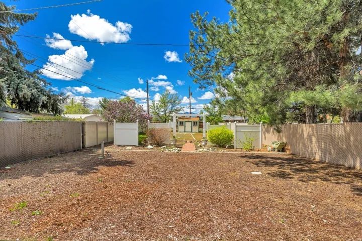 Expansive yard space with wood chip ground cover, fenced perimeter, and mature trees
