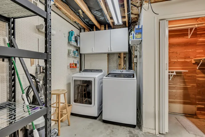 Utility space with pegboard wall, built-in upper cabinetry, and concrete flooring