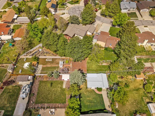 Expansive property featuring a red brick patio, mature trees, and multiple outbuildings