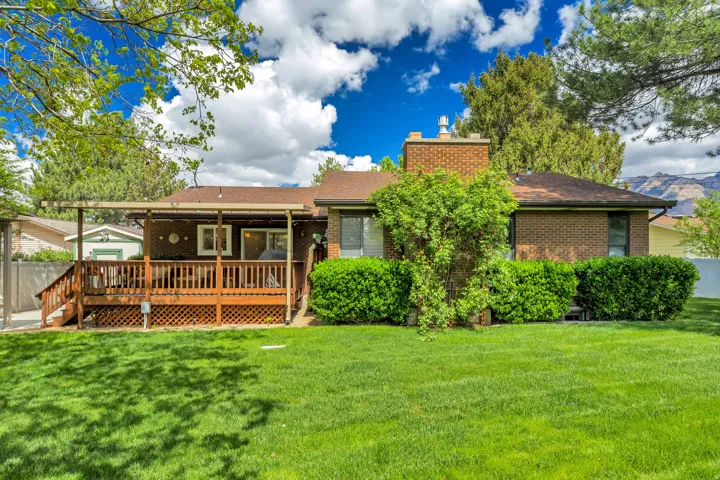 Expansive lawn with mature landscaping and a large wood-finish deck