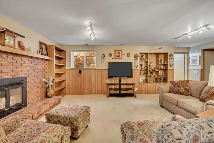 Brick fireplace with hearth, built-in shelving, wood paneling, recessed lighting, and track lighting