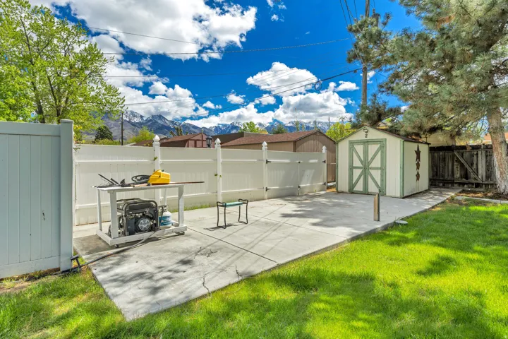 Manicured lawn with a concrete pad, a storage shed, and a privacy fence
