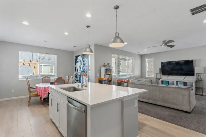 Kitchen island with an undermount sink, stainless steel dishwasher, and pendant lighting