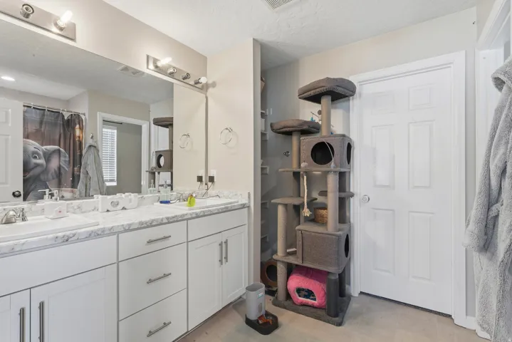 Double vanity with undermount sinks, white cabinetry, and a full-width mirror