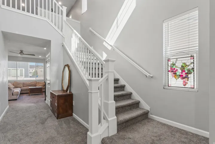 Two-story foyer with a carpeted staircase and white balusters