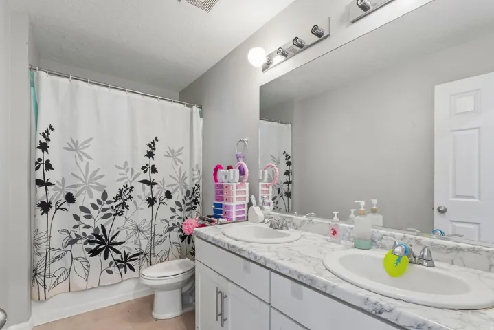Double vanity with white cabinetry, integrated sinks, and patterned countertops