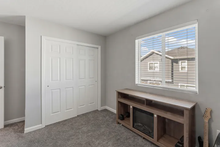 Soft gray wall paint, gray carpet flooring, white trim, and a window with horizontal blinds