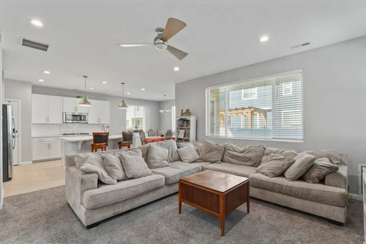 Open-concept living area with a ceiling fan, recessed lighting, and a large window
