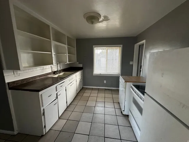 Kitchen featuring white cabinetry, tile flooring, and a window