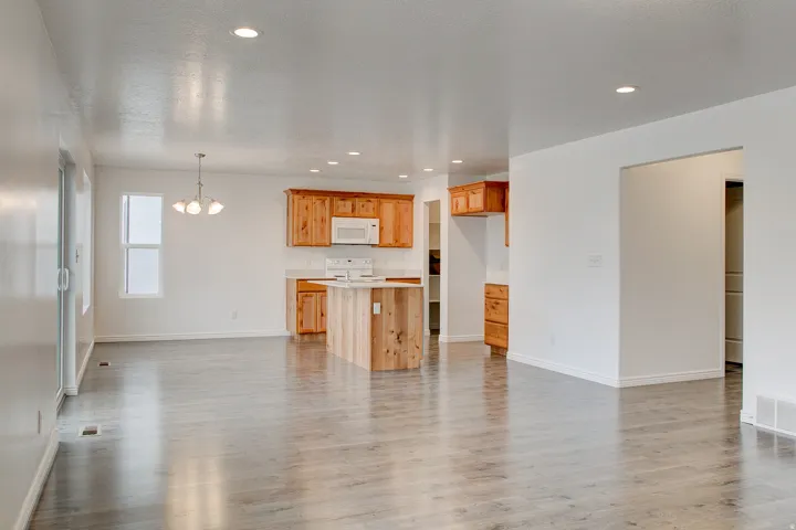Open-concept living space featuring wood-finish flooring, recessed lighting, and a kitchen with wood cabinetry and an island