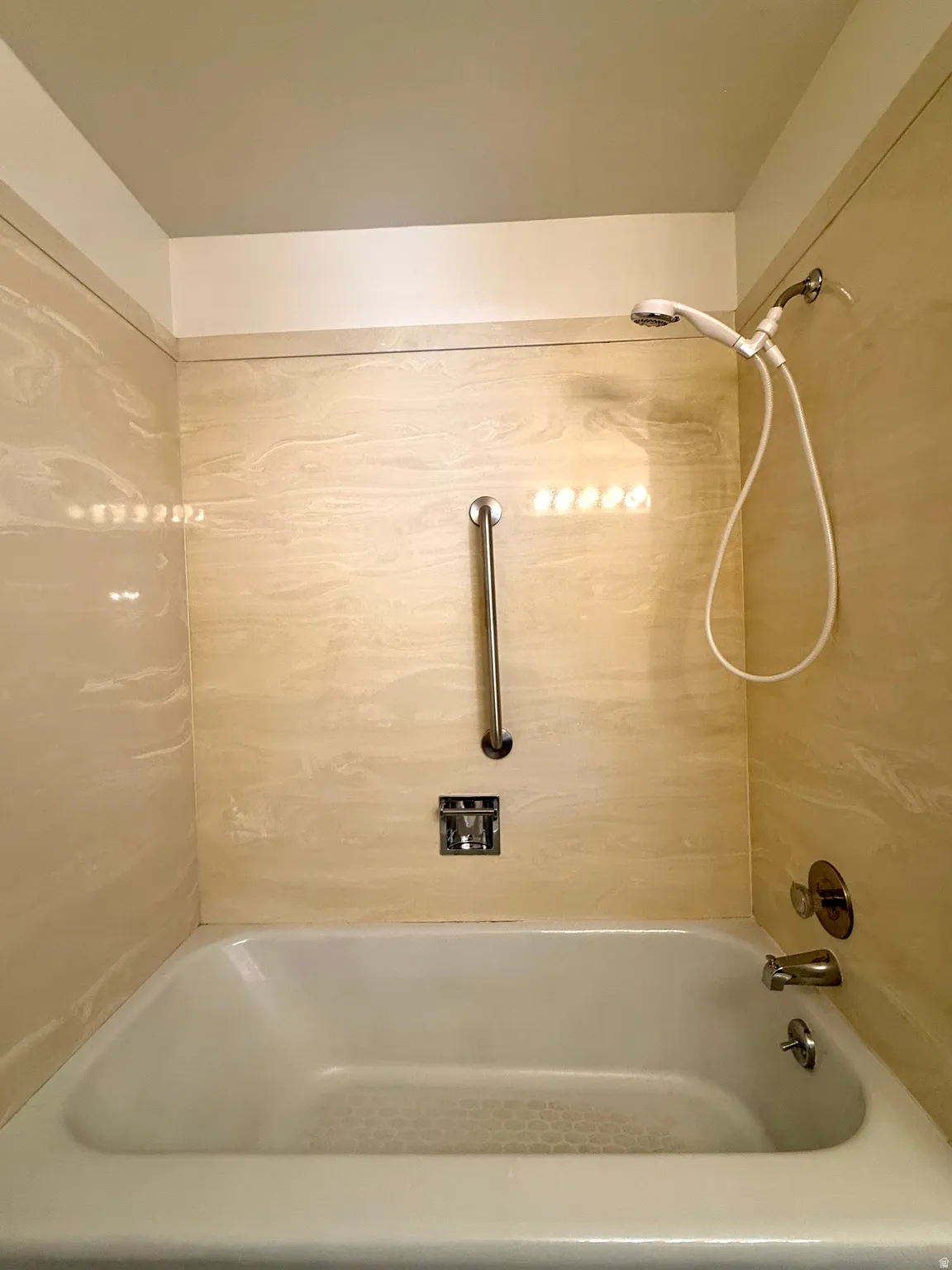 Bathtub with wall-mounted shower head and handheld spray fixture