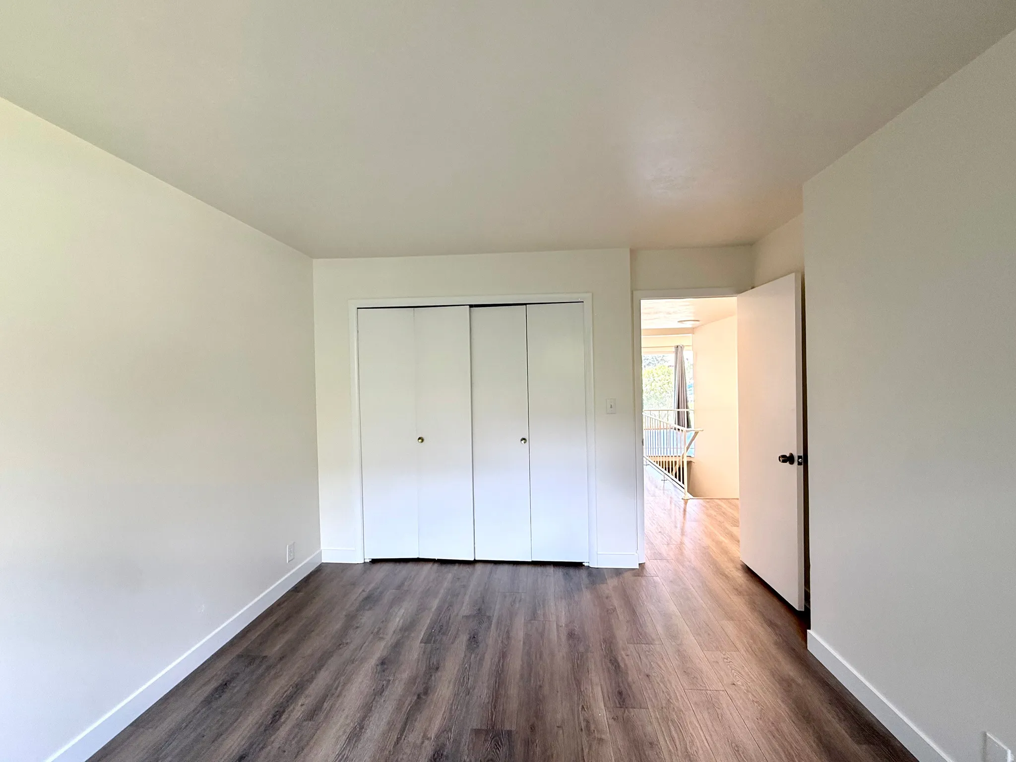 Wood-finish flooring with crisp white baseboards and neutral wall tones