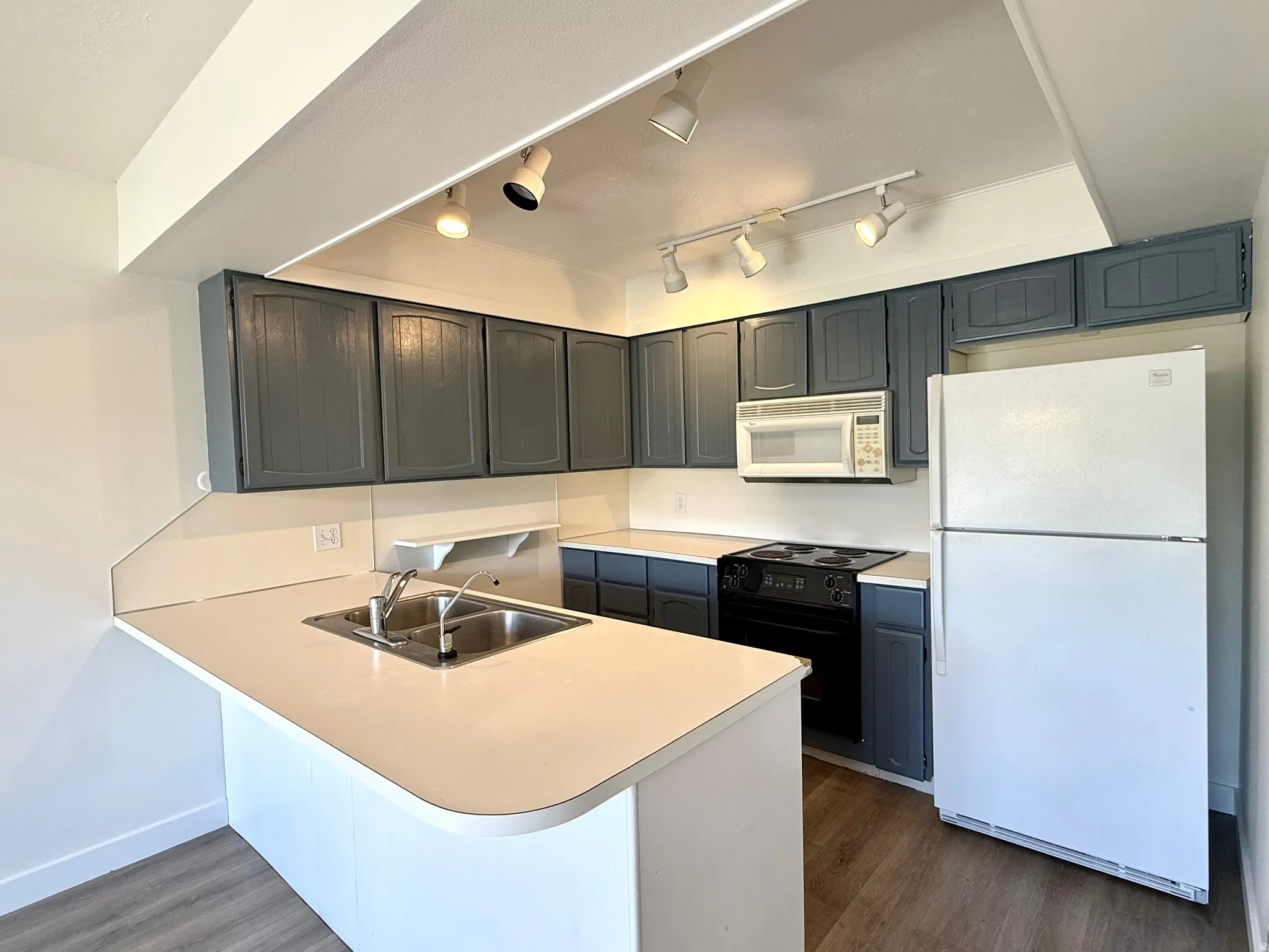 Kitchen featuring gray cabinetry, white countertops, a double basin sink, electric cooktop, and track lighting