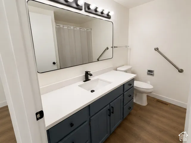 Vanity featuring a matte-finish dark blue cabinet, quartz countertop, integrated rectangular sink, matte black faucet, and large rectangular mirror with an overhead multi-light fixture