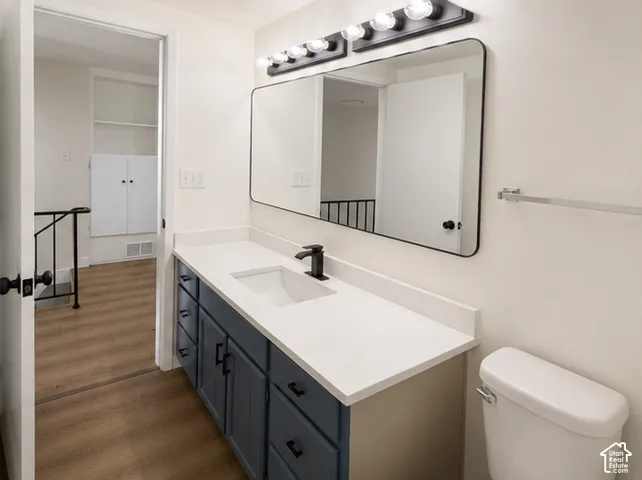 Bathroom featuring a vanity with navy cabinetry, a light-toned solid surface countertop, an undermount sink, a matte black faucet, and a wall-mounted rectangular mirror