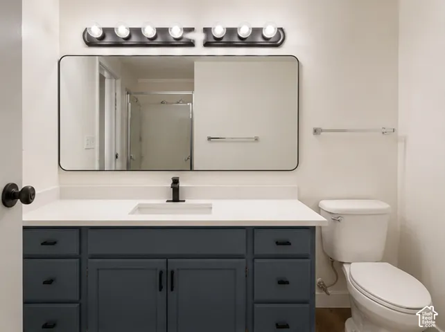Blue-tone vanity with a rectangular sink, white countertop, matte black hardware, and an expansive wall-mounted mirror