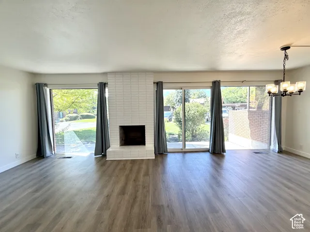 Wood-finish flooring, white brick fireplace, multiple sliding glass doors, and a multi-light chandelier