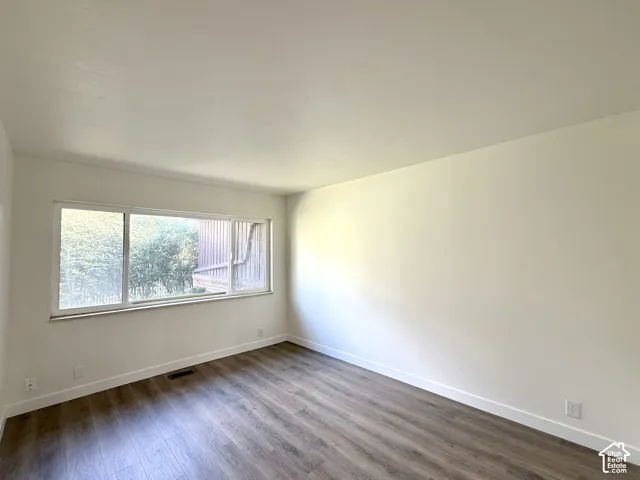 Large window with white frame, wood-finish flooring, and white walls