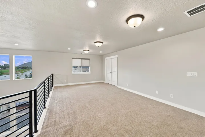 Spacious loft area featuring neutral carpeting and light gray walls.