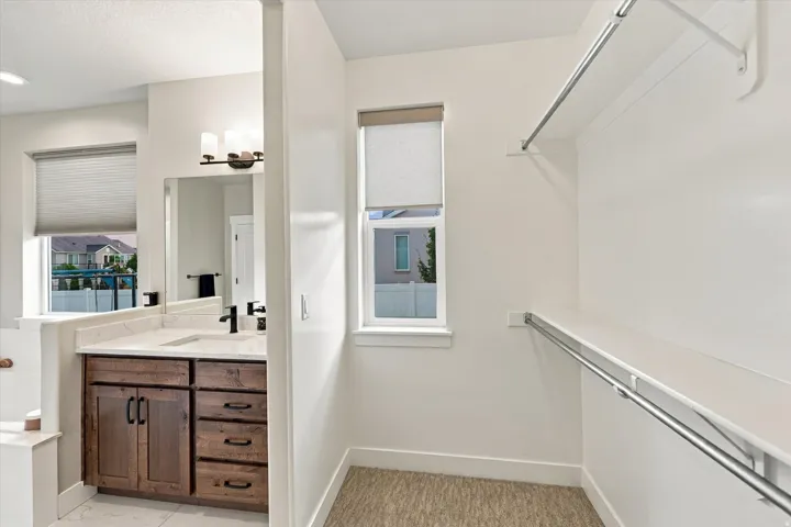 Custom vanity with integrated sink, matte black fixtures, and mirror. Double walk in closets.