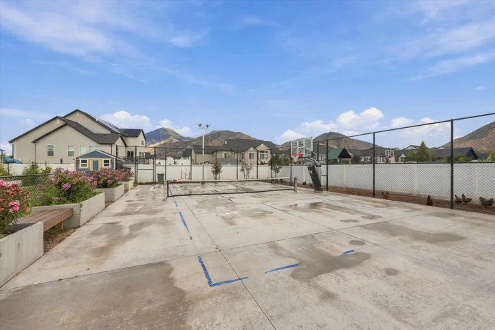 Concrete sport court with basketball hoop and tennis net, concrete planters with integrated bench seating, and a storage shed.