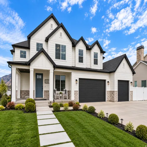 Modern farmhouse exterior with white vertical and horizontal siding, beautiful stone, dark asphalt shingle roofing, and upgraded black framed windows and a wrap around pourch.