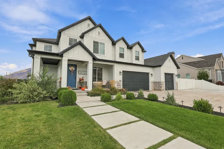 Modern farmhouse exterior featuring white siding, dark trim accents, a prominent covered entry, and multiple attached garages