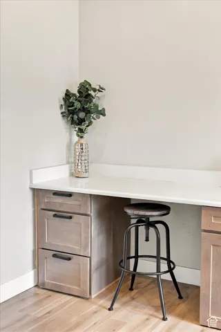 Built-in desk with a solid surface countertop, custom cabinetry, and wood-finish flooring.