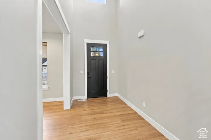 Vaulted entry , wood-finish flooring, white trim, solid paneled door with glass inserts, and light-toned walls with office or front entry room off of entrance.