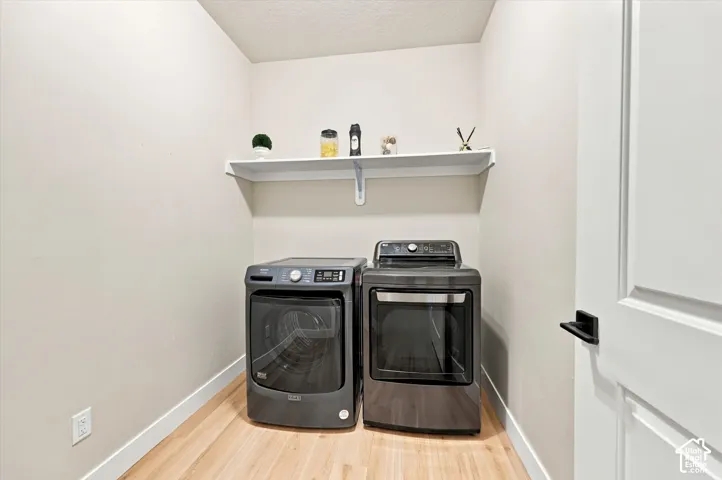 Laundry area featuring light wood-finish flooring, light-toned walls, and a white floating shelf.