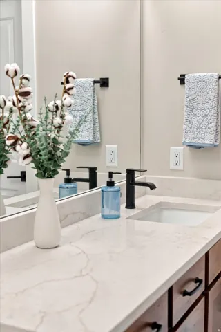 Dual vanity with undermount sinks, stone countertop, matte black faucets, and wood-finish cabinetry with black hardware.