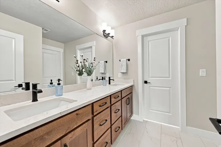 Extra large bathroom. Dual vanity with an integrated rectangular sink, white stone-finish countertop, dark wood-finish cabinetry, and black hardware.