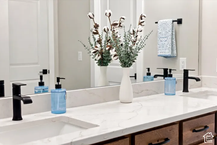 Dual undermount sinks with matte black fixtures, set within a light-toned countertop, and wood-finish cabinetry.