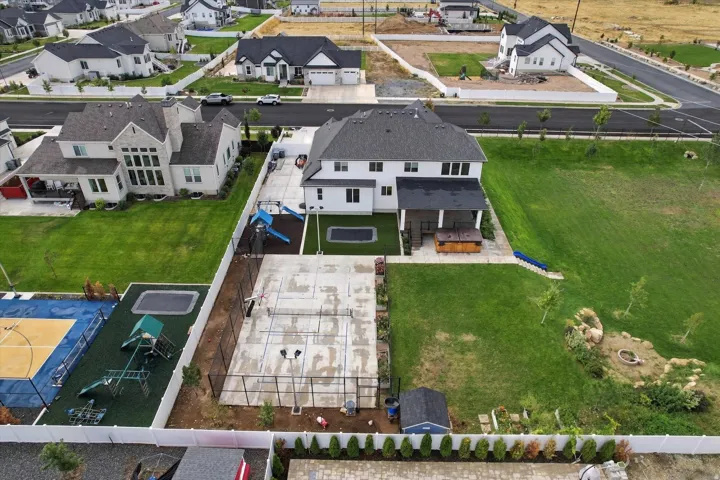 Spacious backyard featuring a covered patio,  sport court, built-in play ground, zipline, and a large turf area