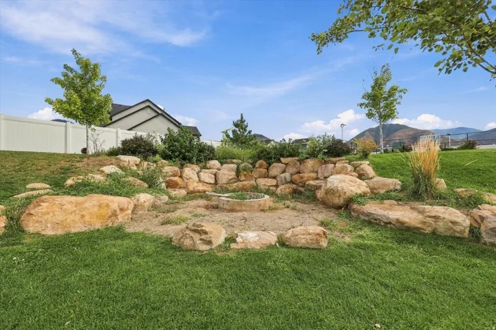 Expansive lawn area with a built-in rock retaining wall and integrated fire pit.