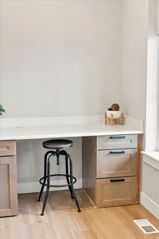 Built-in desk featuring a white countertop, light wood-finish cabinetry, and black drawer pulls.